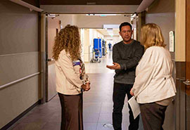 Un hombre y dos mujeres conversan en el pasillo de un hospital